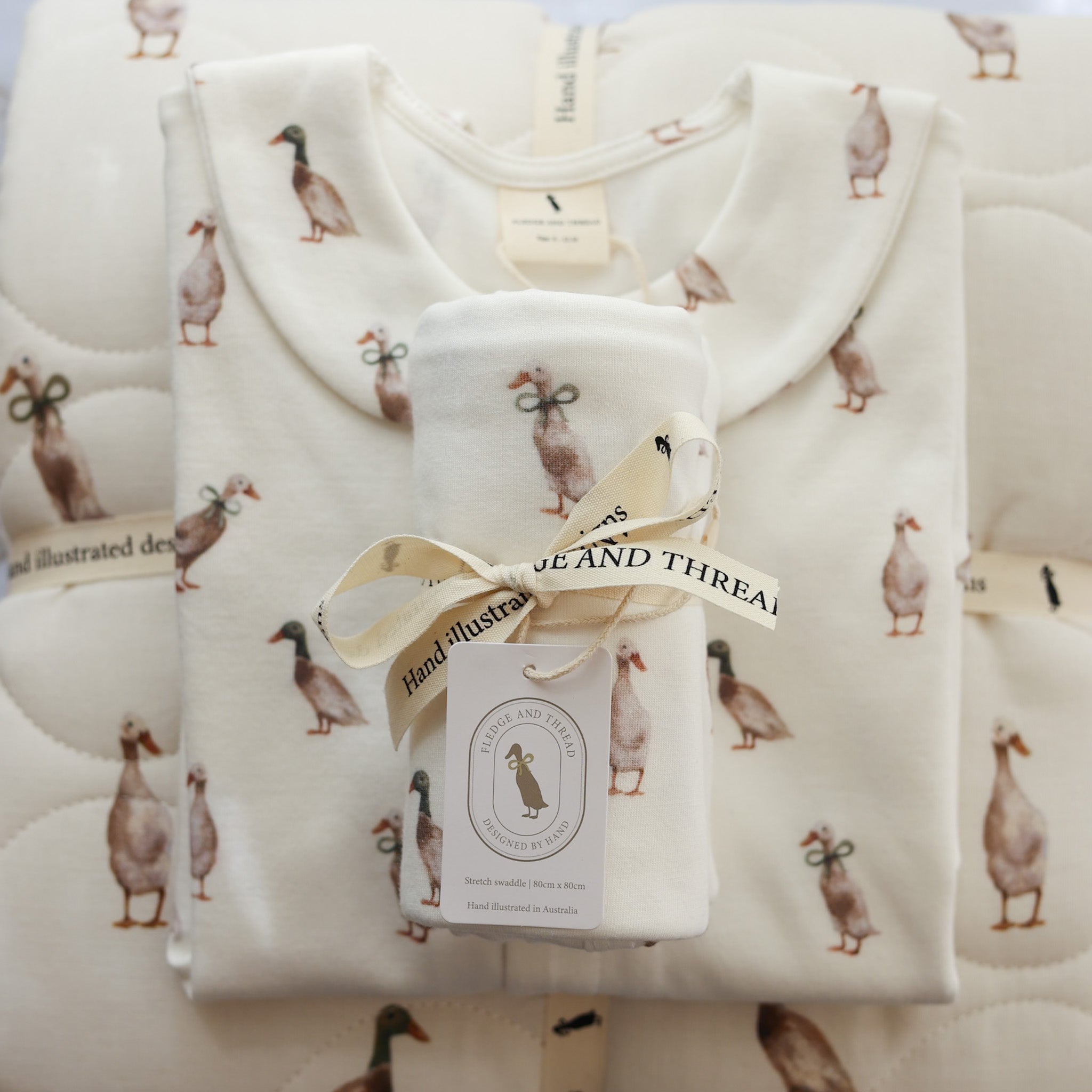 Hand-illustrated duck baby clothing set including romper, babygrow, baby blanket, and bonnet. Soft cotton, designed in Australia for baby gifts and everyday wear.