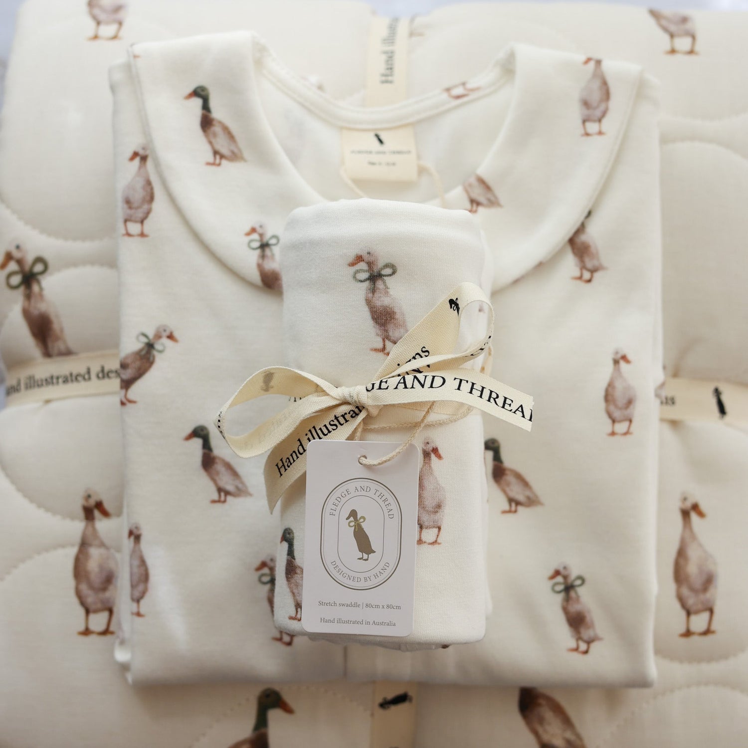 Hand-illustrated duck baby clothing set including romper, babygrow, baby blanket, and bonnet. Soft cotton, designed in Australia for baby gifts and everyday wear.
