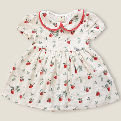 A baby girl's short-sleeve dress with a white base, featuring a red and green cherry print, a red ruffled Peter Pan collar, and a gathered waist.
