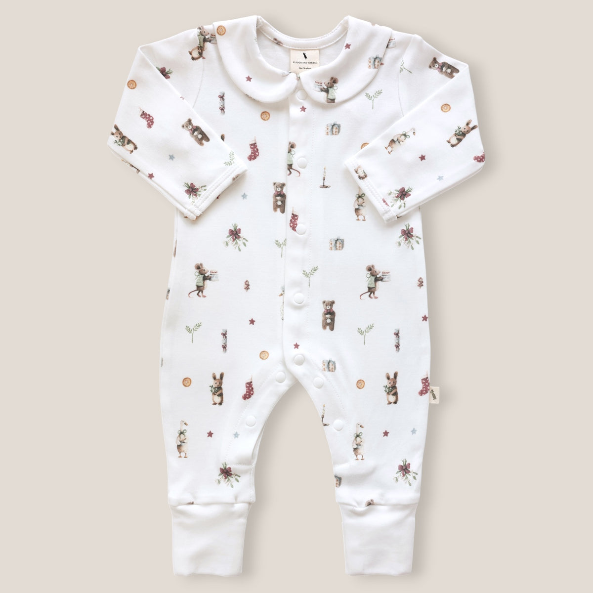 A white long-sleeve baby romper with a button-down front, featuring an all-over print of woodland animals, flowers, and small icons. The romper has a Peter Pan collar and is photographed flat against a solid light beige background.