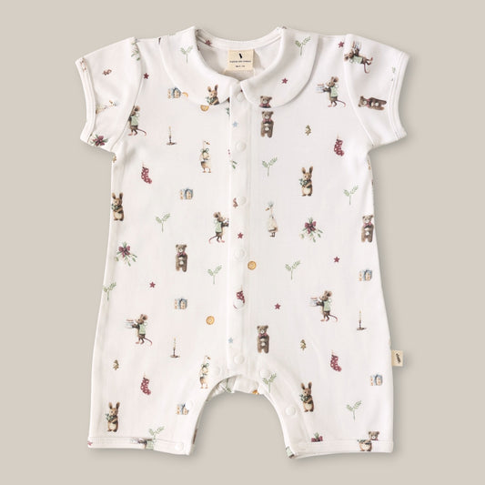 A white short-sleeve baby romper with a button-down front and an all-over whimsical print of bears, rabbits, stars, and small illustrations, laid flat on a neutral beige background.