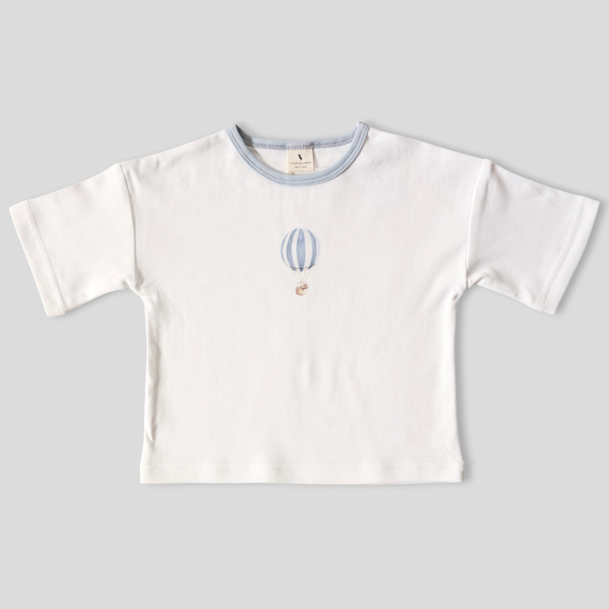 A white short-sleeve baby t-shirt with a light blue ribbed crew neck and a small embroidered hot air balloon motif on the center chest, displayed flat against a neutral gray background.
