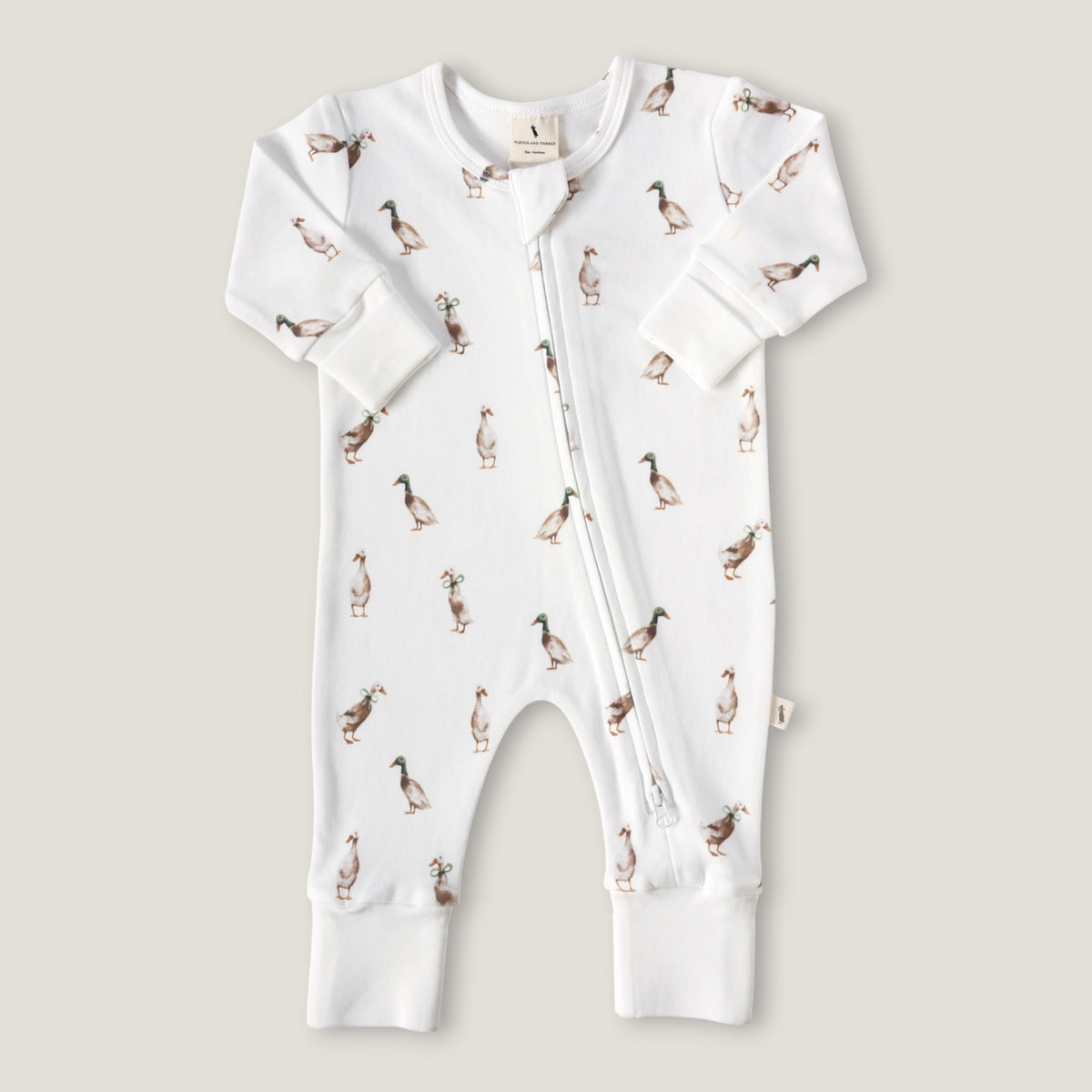 A white long-sleeve baby romper with an all-over duck print, featuring a front zipper and ribbed cuffs and foot.