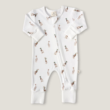 A white long-sleeve baby romper with an all-over duck print, featuring a front zipper and ribbed cuffs and foot.