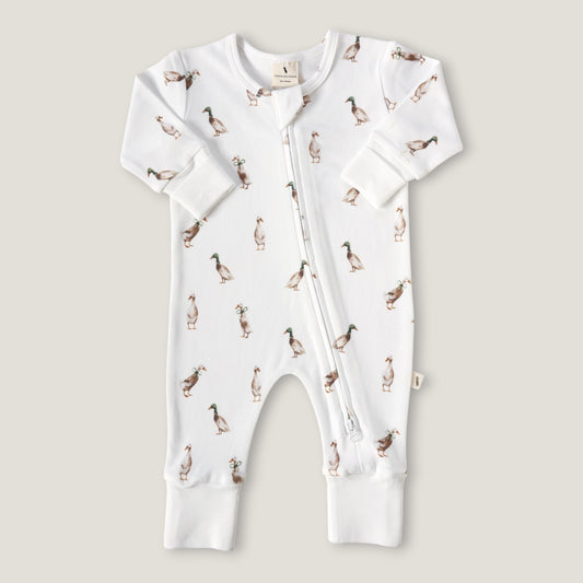 A white long-sleeve baby romper with an all-over duck print, featuring a front zipper and ribbed cuffs and foot.