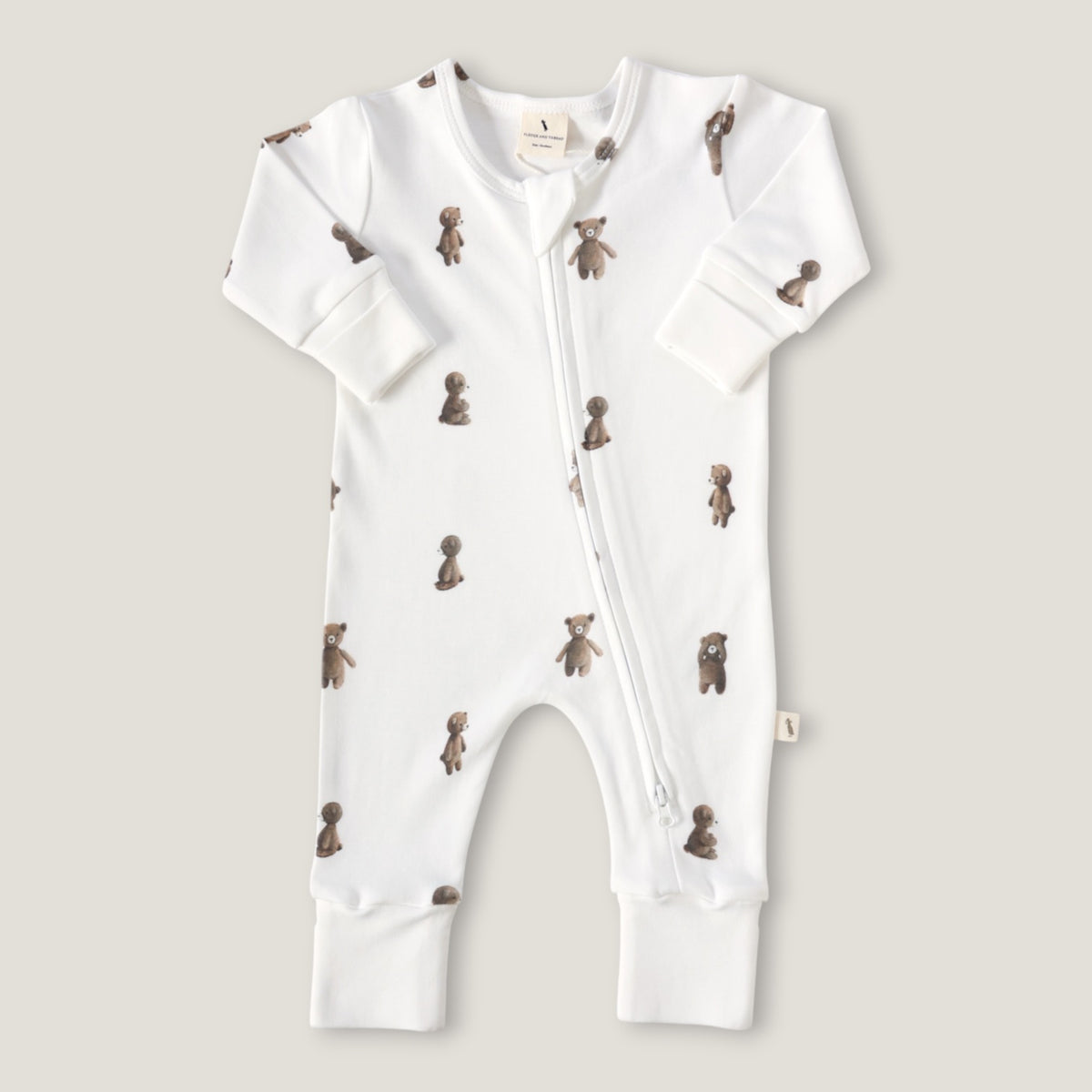 A white long-sleeve baby footless one-piece sleeper with a front zipper and an all-over print of small brown teddy bears, shown flat on a light beige background.